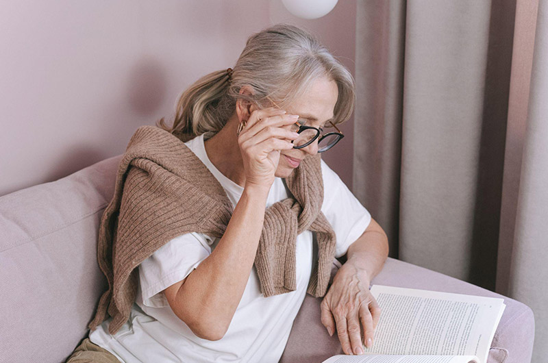 elderly woman reading a book with glasses